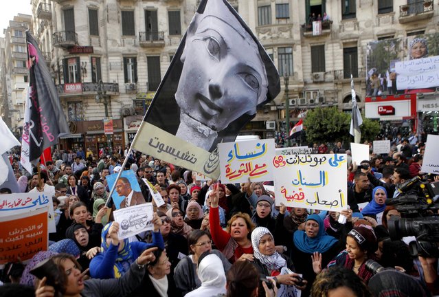 Egyptian women wave a flag showing pharaoh Queen Hatshepsut, the only woman that ruled Egypt, and anti-Muslim Brotherhood banners during a demonstration in Cairo, Egypt, Friday, March 8, 2013, marking International Women's Day. Arabic reads, “women with revolution”, “women are owner of a message”. (Photo by Amr Nabil/AP Photo)