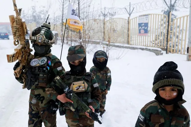 Children of Taliban members, dressed in military uniforms, hold toy weapons as they walk on a snow-covered street in Kabul, Afghanistan on January 29, 2023. (Photo by Ali Khara/Reuters)