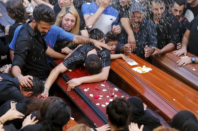 Relatives of the Safwan family, that drowned on a boat carrying them from Turkey to Greece, mourn on their coffins during their funeral in Beirut's southern suburb of Ouzai, Lebanon October 22, 2015. Seven members of a Lebanese family who died trying to reach Greece by boat were buried on Thursday in Beirut and survivors described watching their loved ones perish before their eyes. (Photo by Mohamed Azakir/Reuters)
