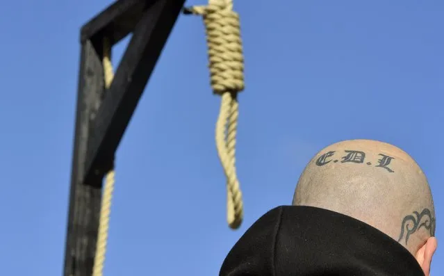 A supporter of the English Defence League with a tattoo on his head stands by a replica hangman's noose and gallows during a protest outside the Old Bailey courthouse in London, in this February 26, 2014 file photo. (Photo by Toby Melville/Reuters)