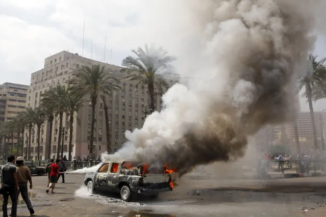 Egyptians extinguish a burning police vehicle, which has been set afire by angry protesters in Tahrir Square, once the epicenter of protests against former President Mubarak, in Cairo, Egypt, Monday, March 18, 2013. Egypt is currently mired in another wave of protests, clashes and unrest that have plagued the country since the ouster of authoritarian leader Hosni Mubarak in the pro-democracy uprising two years ago. (Photo by Amr Nabil/AP Photo)