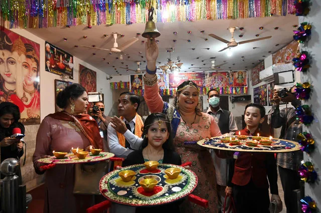 Hindu women hold clay-lamps during a ceremony to celebrate Diwali, the festival of lights, at a Krishna temple in Lahore, Pakistan, Saturday, November 14, 2020. The Hindu festival of lights, Diwali celebrates the spiritual victory of light over darkness. (Photo by Arif Ali/AFP Photo)