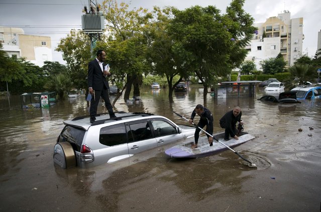 Israelis on a small motor boat help a motorist (L) after his vehicle got stuck on a flooded street in the southern city of Ashkelon, Israel, November 9, 2015. (Photo by Amir Cohen/Reuters)