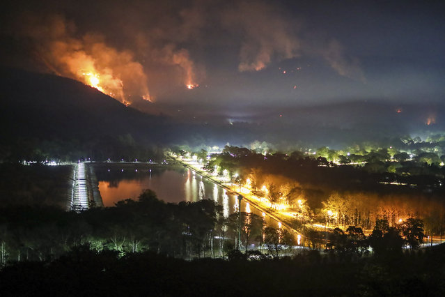 Fire and smoke rise from a forest fire at Nakhon Nayok province province, 114 kilometers (70 miles) northeast of Bangkok. Thailand, Thursday, March 30, 2023. The fire had engulfed large areas of two mountains by Thursday, and the authorities were trying to contain its spread. (Photo by Nava Sangthong/AP Photo)
