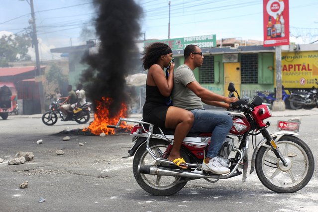 A motorcyclist rides past a burning barricade during a protest against gang-related violence and to demand the resignation of Haiti's transitional presidential council, in Port-au-Prince, Haiti, on May 15, 2025. (Photo by Jean Feguens Regala/Reuters)