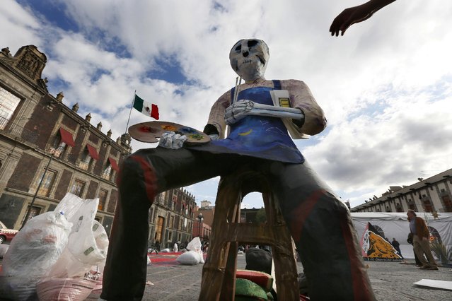 Skeletons decorate Mexico City's main square, the Zocalo, as part of the Day of the Dead festivities in Mexico City, Thursday, October 27, 2016. The holiday honors the dead as friends and families gather in cemeteries to decorate their loved ones' graves and hold vigil through the night on Nov. 1 and 2. (Photo by Marco Ugarte/AP Photo)