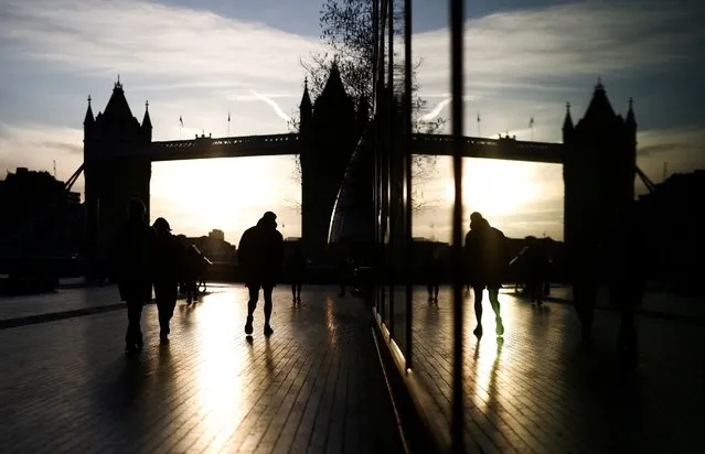 People walk near the Tower Bridge during sunrise in London, Britain on April 13, 2023. (Photo by Henry Nicholls/Reuters)
