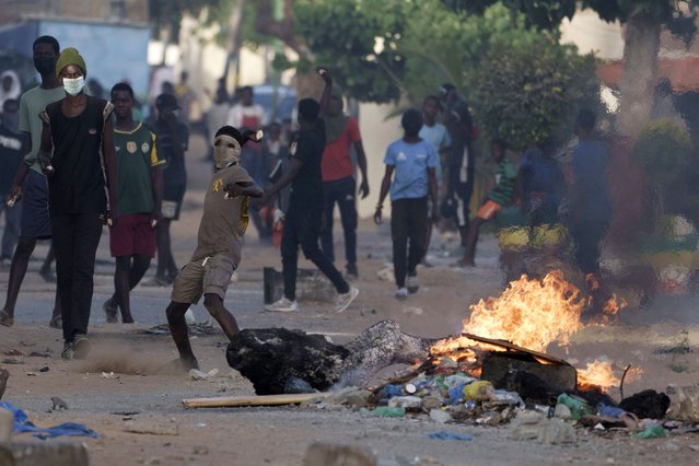 A demonstrator throws a rock at police during a protest at a neighborhood in Dakar, Senegal, Saturday, June 3, 2023. The clashes first broke out later this week after opposition leader Ousmane Sonko was convicted of corrupting youth and sentenced to two years in prison. (Photo by Leo Correa/AP Photo)
