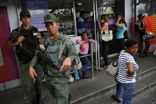 National guards stand at a supermarket entrance as people line up outside in Caracas January 19, 2015. (Photo by Jorge Silva/Reuters)
