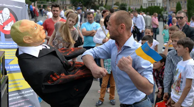 A man punches an effigy of Russian President Vladimir Putin on May 31, 2015 on a street in the western Ukrainian city of Lviv. (Photo by Yuriy Dyachyshyn/AFP Photo)