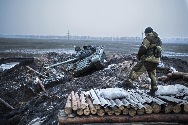 A pro-Russian rebel guards a captured former Ukrainian Army checkpoint outside Vuhlehirsk, Donetsk region, eastern Ukraine, Thursday, February 5, 2015. The rebels have closed in around the town in a strategy they triumphantly refer to as the Debaltseve cauldron. Separatists recently burst through government lines in the rural settlement of Vuhlehirsk. (Photo by Vadim Braydov/AP Photo)