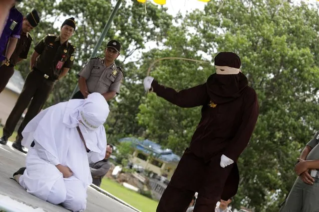 An Acehnese woman (L) faces a public caning punishment, for having a s*x relationship outside marriage, in Jantho, Aceh, Indonesia, 20 July 2018. (Photo by Hotli Simanjuntak/EPA/EFE)