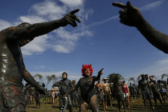 A mud covered reveler dances during the traditional “Bloco da Lama” or “Mud Block” carnival party, in Paraty, Brazil, Saturday, February 14, 2015. (Photo by Leo Correa/AP Photo)