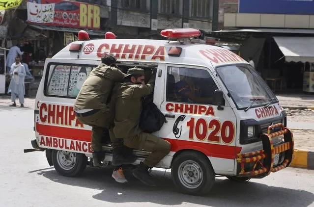 Police officers hang on to an ambulance carrying their colleagues that were injured during a clash with supporters of Tehreek-e-Labiak Pakistan, a banned Islamist party, protesting the arrest of their party leader Saad Rizvi, in Lahore, Pakistan, Sunday, April 18, 2021. (Photo by K.M. Chaudary/AP Photo)