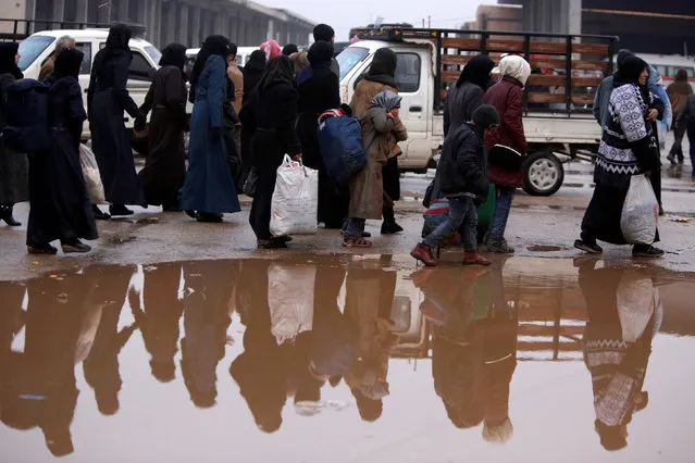 Syrians evacuated from eastern Aleppo walk with their belongings near a puddle of water in government controlled Jibreen area in Aleppo, Syria November 30, 2016. (Photo by Omar Sanadiki/Reuters)