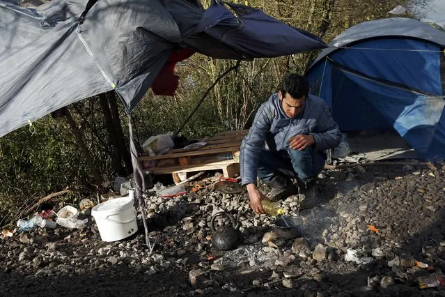 A migrant prepares a meal next to shelters in a muddy field called the Grande-Synthe jungle, near Dunkirk, northern France, January 12, 2016. (Photo by Benoit Tessier/Reuters)