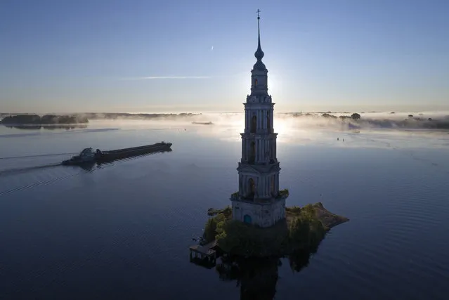 A cargo ship floats past the famous Kalyazin Bell Tower, part of the submerged monastery of St. Nicholas, in the town of Kalyazin located on the Volga River, 180 km (111 miles) north-east of Moscow, Russia, early Thursday, August 9, 2018. After the construction of the Uglich Dam in 1939 to form the Uglich Reservoir, the old parts of Kalyazin, including several medieval structures, were submerged under the reservoir's waters. (Photo by Dmitri Lovetsky/AP Photo)