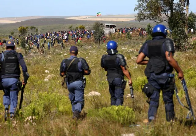 Police officials keep an eye on protesters from the Railton informal settlement protesting over the high electricity tariffs and the municipality's indigent grant, in Swellendam, 200km outside Cape Town, South Africa on September 20, 2023. (Photo by Esa Alexander/Reuters)