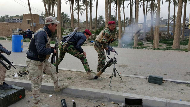 Iraqi security forces fire at Islamic State group positions during clashes in Ramadi, 70 miles (115 kilometers) west of Baghdad, Iraq, Saturday, January 23, 2016. The Islamic State group, which controls large parts of Syria and Iraq where it declared an Islamic caliphate in June 2014, suffered several defeats recently in both countries, including the loss of the Iraqi city of Ramadi and parts of northern and northeastern Syria over the past months. (Photo by AP Photo)