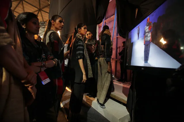 Models waiting for their turn backstage watch others on a screen during the Amazon India Fashion Week in New Delhi, India, Friday, March 27, 2015. (Photo by Altaf Qadri/AP Photo)