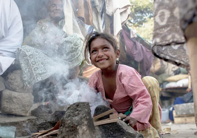 A Pakistan girl tries to light fire on a makeshift stove for cooking outside her shanty home in Karachi, Pakistan, February 12, 2015. (Photo by Shakil Adil/AP Photo)