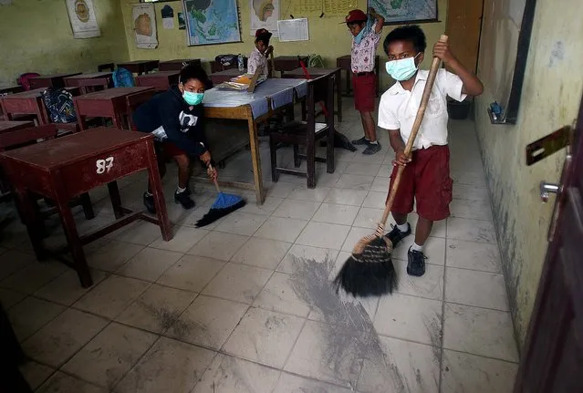 Students sweep volcanic ash off the floor of their classroom at an elementary school in Tiga Nderket. (Photo by Binsar Bakkara/Associated Press)
