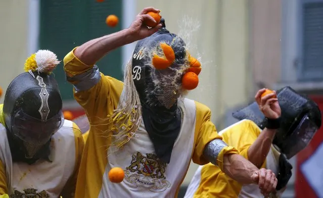 A participant is hit by an orange during an annual carnival battle in the northern Italian town of Ivrea February 7, 2016. Dressed up as Middle Age kings' guards, a group of men ride in a horse-drawn carriage and pelt “foot soldiers” with oranges as thousands of people gather to re-enact a Middle Age battle when the townsfolk of Ivrea overthrew an evil king. In a strange twist, instead of swords and cross bows, these days the weapons of choice are oranges. (Photo by Stefano Rellandini/Reuters)