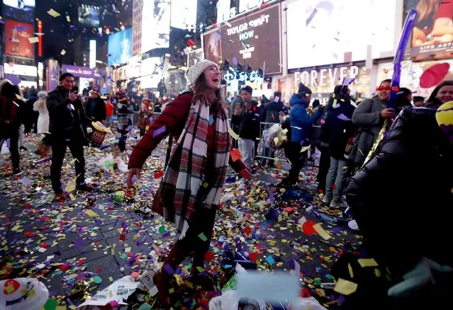 A woman runs after confetti picked up by wind while celebrating the new year at Times Square, Sunday, January 1, 2017, in New York. (Photo by Julio Cortez/AP Photo)