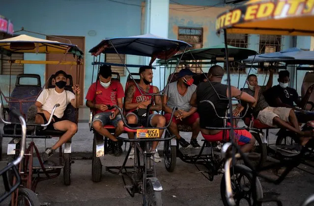 Bicycle taxi drivers sit on their bikes as they wait for customers in Old Havana, Cuba, Monday, July 12, 2021, the day after protests against food shortages and high prices amid the coronavirus crisis. (Photo by Eliana Aponte/AP Photo)