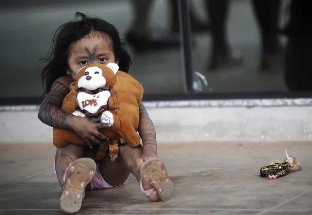 A Munduruku Indian child sits outside Congress as members of the tribe protest against the law project called PEC 215 being debated by the Lower House in Brasilia, December 11, 2013. According to the protesters, the proposed PEC 215 would transfer the power to demarcate Indian lands from the government to Congress, as desired by the lobby which backs ranchers who hold title top properties deemed to be historically Indian ancestral lands. (Photo by Lunae Parracho/Reuters)