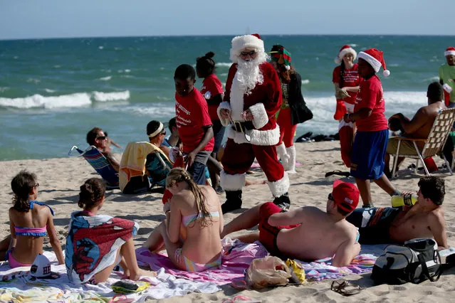 Tom Tapp dressed as Santa Claus walks along the beach passing out candy canes and posing for pictures with beach goers on December 20, 2013 in Fort Lauderdale, Florida. Tapp has been visiting the beach as Santa Claus just before Christmas for over 25 years.  (Photo by Joe Raedle/Getty Images)