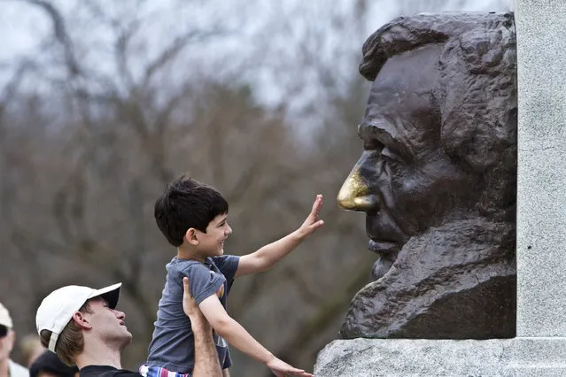 In this Wednesday, April 8, 2015 photo, Tim Hinrichs, of California, lifts his six-year-old son, Alex, to rub the nose of a bust of President Abraham Lincoln outside his tomb in Springfield, Ill. Local legend says rubbing the nose brings good luck. (Photo by Randy Squires/AP Photo)