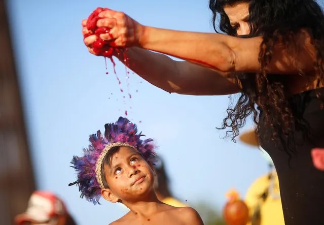 An indigenous child observes as an activist gives an art performance during a protest on the first day of the Brazil's Supreme Court trial of a landmark case on indigenous land rights in Brasilia, Brazil on August 25, 2021. (Photo by Adriano Machado/Reuters)