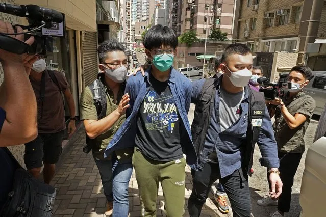 A student of Hong Kong University, center with green mask, is escorted by police officers after a home search in Hong Kong Wednesday, August 18, 2021. Four members of a Hong Kong university student union were arrested Wednesday on accusations of advocating terrorism when they paid tribute to an attacker who stabbed a police officer and then killed himself, police said. (Photo by Vincent Yu/AP Photo)