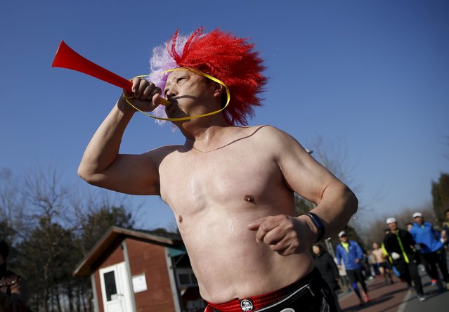 A participant blows a horn while running in the “Half-Naked Marathon” at Olympic Forest park in Beijing, China, February 28, 2016 (Photo by Kim Kyung-Hoon/Reuters)