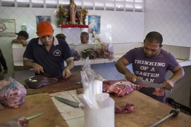 Butchers cut meat at a wholesale food market in Caracas, Venezuela, Monday, January 28, 2019. (Photo by Rodrigo Abd/AP Photo)