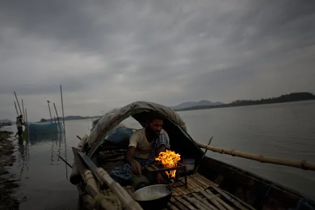 An Indian fisherman lights a stove to prepare food before he goes for fishing in a boat in the river Brahmaputra in Gauhati, Assam state, India, Sunday, April 19, 2015. Brahmaputra is one of Asia's largest rivers, which passes through China's Tibet region, India and Bangladesh before converging into the Bay of Bengal. (Photo by Anupam Nath/AP Photo)