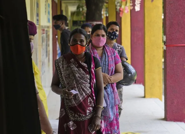 People stand in a queue to receive the COVID-19 vaccine in New Delhi, India, Tuesday, September 21, 2021. India, the world's largest vaccine producer, will resume exports and donations of surplus coronavirus vaccines in October after halting them during a devastating surge in domestic infections in April, the health minister said Monday. (Photo by Manish Swarup/AP Photo)