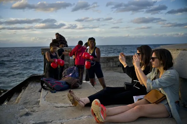 In this January 30, 2017 photo, boxers Idamerys Moreno, left, and Legnis Cala, get ready for a photo session, as tourists take photos of the sunset, on Havana's sea wall in Cuba. Female athletes in Cuba have made strides in many other sports, including wrestling, judo and most recently, weightlifting, but not in boxing. (Photo by Ramon Espinosa/AP Photo)