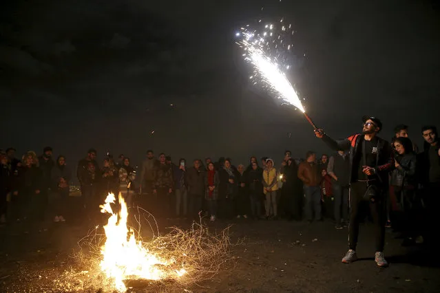 A man holds up a firework during Chaharshanbe Souri, or Wednesday Feast, an ancient Festival of Fire, on the eve of the last Wednesday of the solar Persian year, in Tehran, Iran, Tuesday, March 19, 2019. (Photo by Ebrahim Noroozi/AP Photo)
