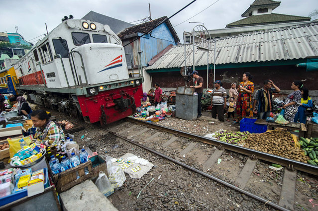 A train moves slowly through a traditional market in Surabaya on March 18, 2016. Indonesia's central bank on March 17 cut its key interest rate for the third straight month, encouraged by lower inflation and a stronger currency in Southeast Asia's top economy. (Photo by Juni Kriswanto/AFP Photo)