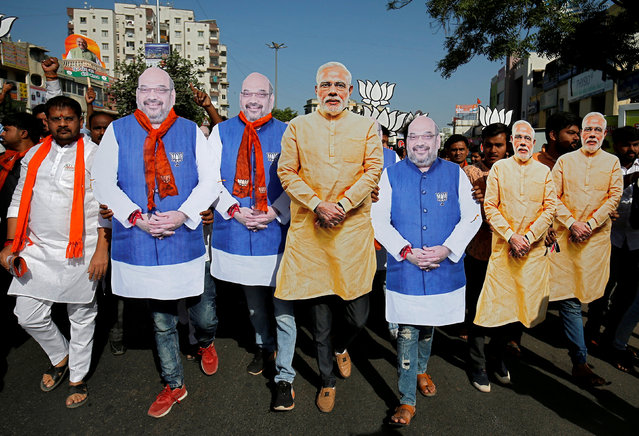 Supporter of India's ruling Bharatiya Janata Party (BJP) wearing cut-outs of Prime Minister Narendra Modi and the party president Amit Shah walk during an election campaign in Ahmedabad, India, April 11, 2019. (Photo by Amit Dave/Reuters)