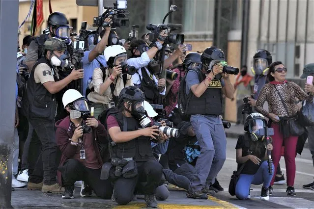 Journalists cover clashes between police and anti-government protesters in Lima, Peru, Tuesday, January 24, 2023. Protesters are seeking the resignation of President Dina Boluarte, the release from prison of ousted President Pedro Castillo, immediate elections and justice for demonstrators killed in clashes with police. (Photo by Martin Mejia/AP Photo)