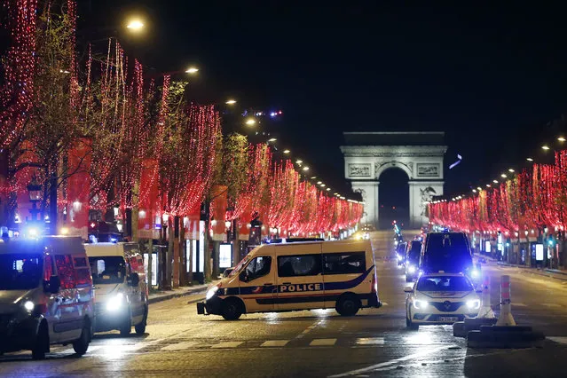Police vans are parked on the Champs Elysees avenue during the New Year's Eve, in Paris, Thursday, December 31, 2020. As the world says goodbye to 2020, there will be countdowns and live performances, but no massed jubilant crowds in traditional gathering spots like the Champs Elysees in Paris and New York City's Times Square this New Year's Eve. (Photo by Thibault Camus/AP Photo)