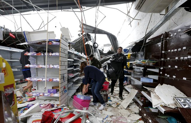 People clean up debris in a supermarket in Dolores the day after the city was hit by a tornado, April 16, 2016. (Photo by Andres Stapff/Reuters)