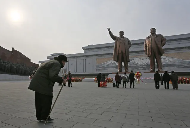 A North Korean elderly man bows before the statues of North Korea's late leader Kim Jong Il, right, and his father, North Korea's founder Kim Il Sung, which tower over the capital Pyongyang on a hill, North Korea, Sunday, February 16, 2014. (Photo by Vincent Yu/AP Photo)