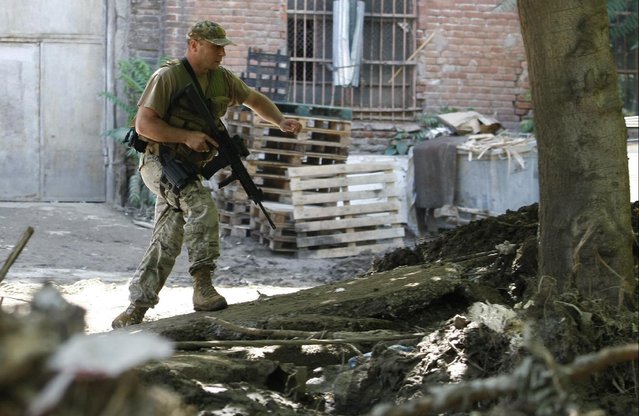 An armed police officer walks near a Zoo in Tbilisi, Georgia, Wednesday, June 17, 2015. Police in the ex-Soviet republic of Georgia reported that a tiger that broke loose after severe flooding at the Tbilisi Zoo was hiding at an abandoned factory when it mauled a man to death Wednesday before being shot by police. (AP  Photo/Shakh  Aivazov)