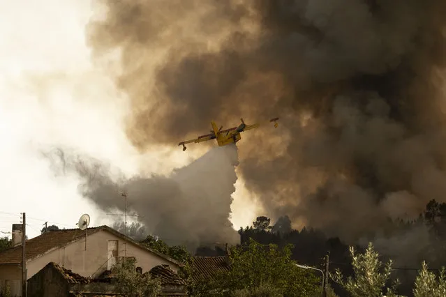 An airplane operates over a fire at the village of Chaveira, near Macao, in central Portugal on Monday, July 22, 2019. More than 1,000 firefighters are battling a major wildfire amid scorching temperatures in Portugal, where forest blazes wreak destruction every summer. About 90% of the fire area in the Castelo Branco district, 200 kilometers (about 125 miles) northeast of the capital Lisbon, has been brought under control during cooler overnight temperatures, according to a local Civil Protection Agency commander. (Photo by Sergio Azenha/AP Photo)