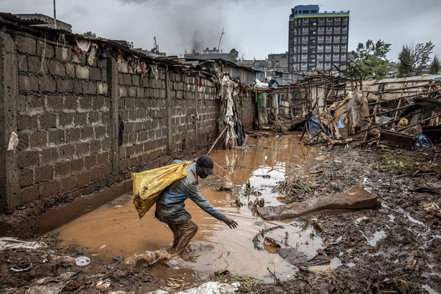 A man carries some belongings while walking on muddy waters in an area heavily affected by floods following torrential rains at the Mathare informal settlement in Nairobi, on April 25, 2024. Torrential rains triggered floods and caused chaos across Kenya, blocking roads and bridges and engulfing homes in slum districts. The death toll from flash floods in Kenya's capital Nairobi has risen to 13 on April 25, 2024, police said. Kenyans have been warned to stay on alert, with the forecast for more heavy rains across the country in the coming days. (Photo by Luis Tato/AFP Photo)