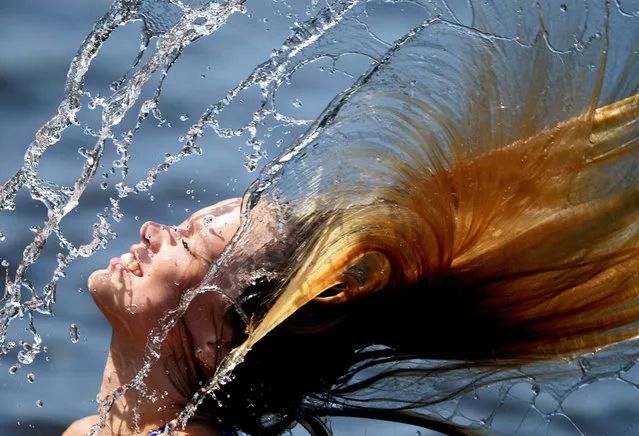 Luise, 21 throws her wet hair in the air at the Strandbad Babelsberg in Potsdam, Germany, 02 July 2015. The summer is hitting above 30 degrees. (Photo by Ralf Hirschberger/EPA)